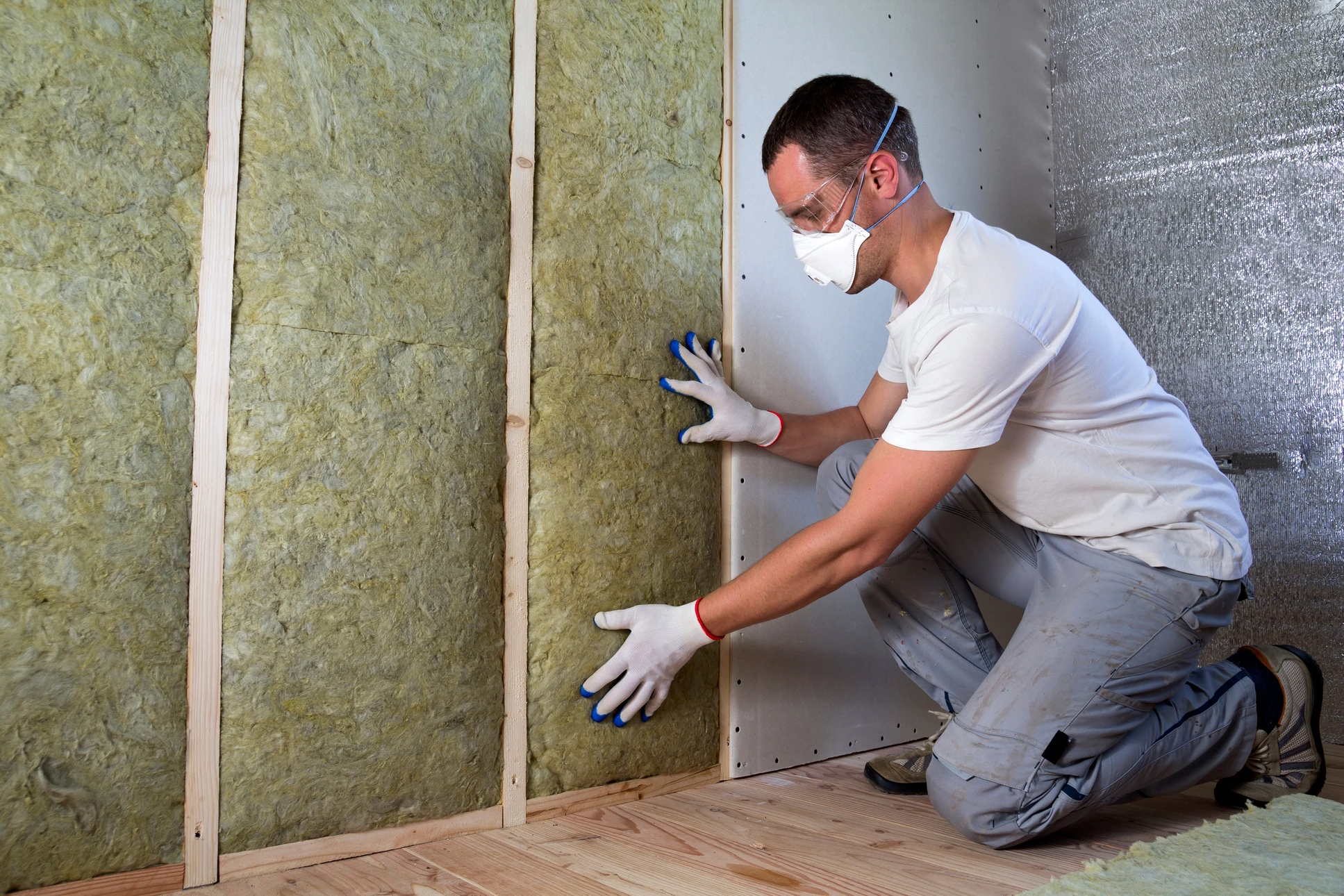 Ouvrier en bâtiment installant l'isolation thermique d'un mur intérieur