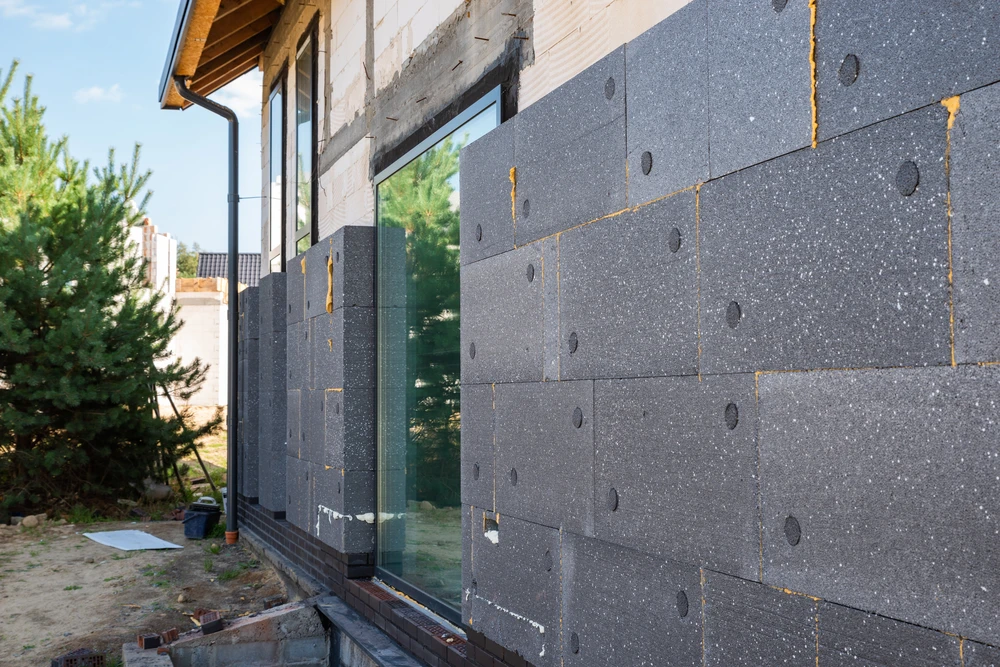 Chantier de construction extérieur avec pose d'isolation thermique par l'extérieur sur façade de maison individuelle