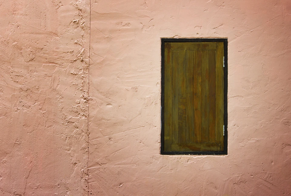 Façade extérieure d'un bâtiment avec mur en crépi rose saumon présentant des fissures et imperfections